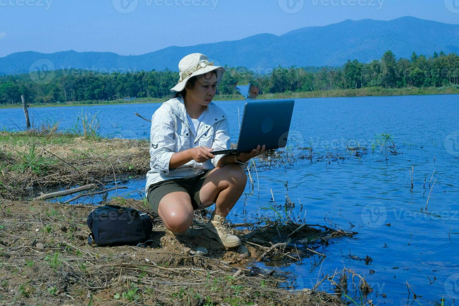 femmina ambientalista utilizzando il computer portatile computer per disco patogeno analisi nel naturale acqua. acqua e ecologia concetto foto