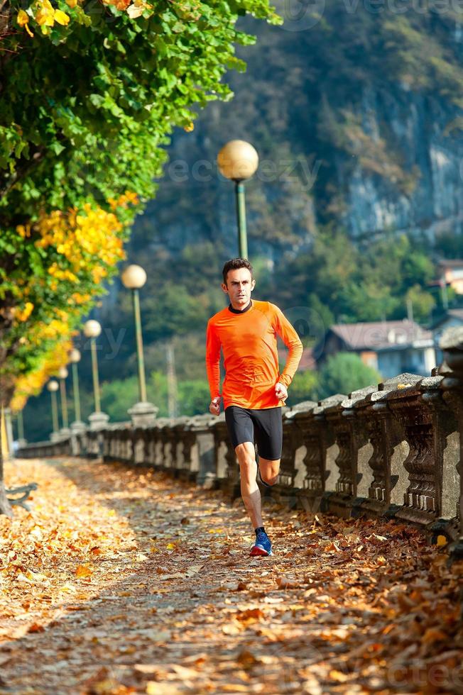 uomo atleta corre in autunno tra le foglie foto