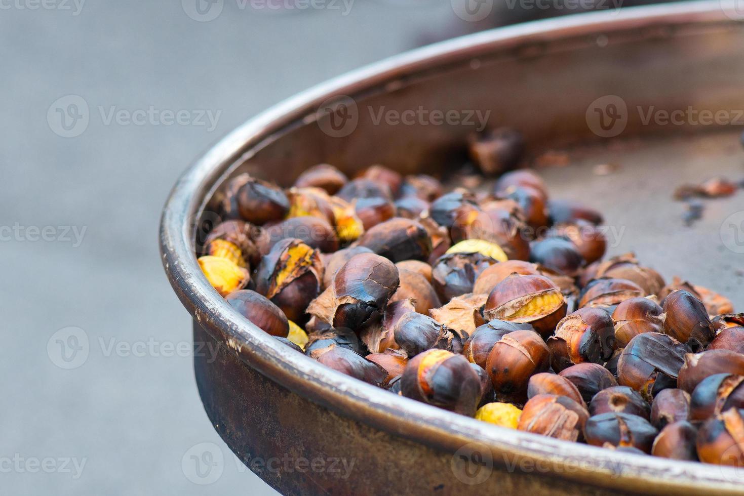 castagne alla griglia per la vendita in una bancarella del mercato foto