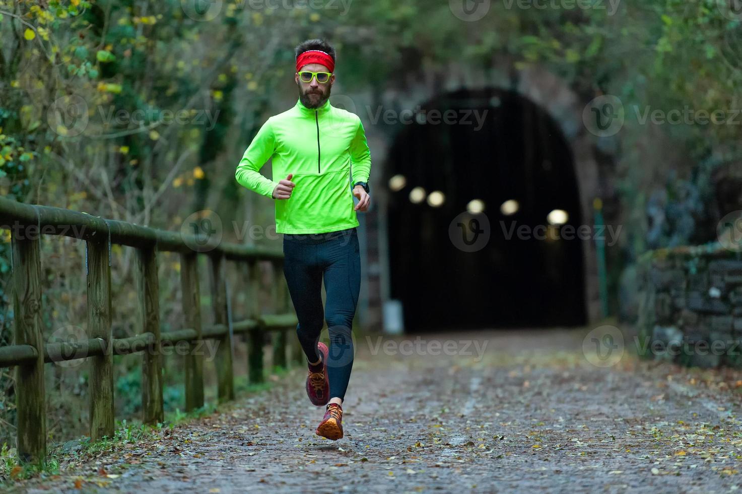 l'uomo atleta corre sulla pista ciclabile tra i tunnel in autunno foto