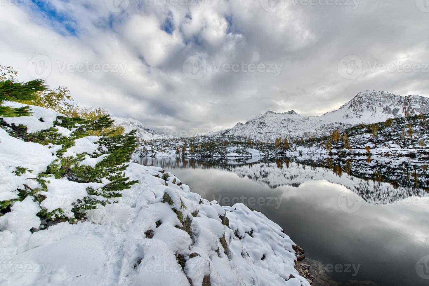 camminando accanto al lago alpino con la neve foto