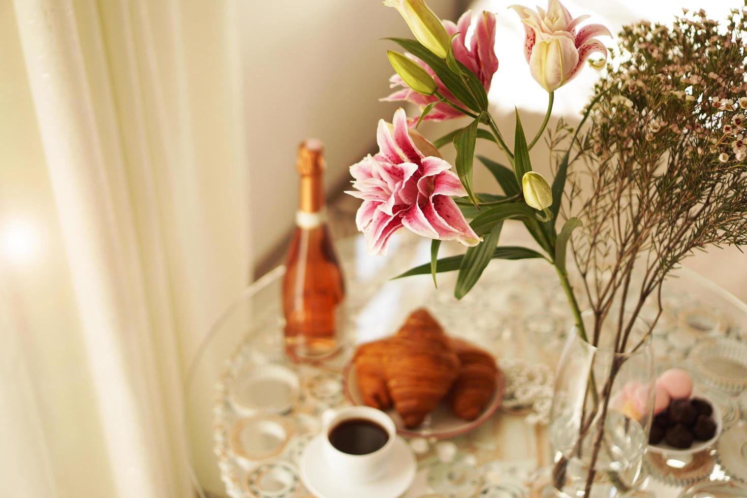 mazzo di gigli. tazza di caffè, croissant e vino foto