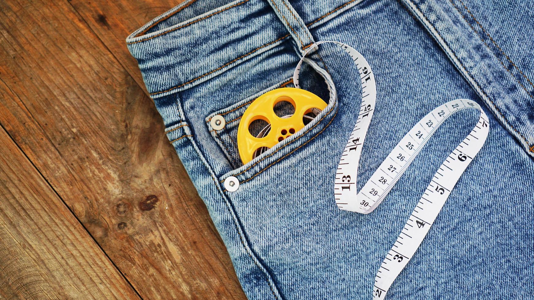 blue jeans e un metro a nastro. concetto di denim dimagrante o cucito foto