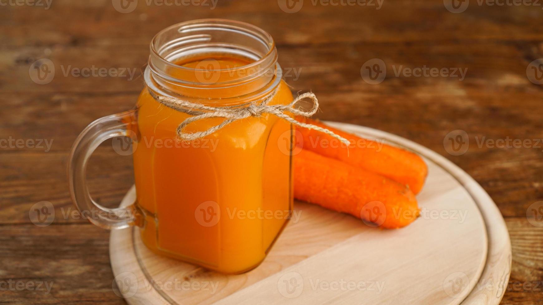 succo di carota su un fondo di legno foto