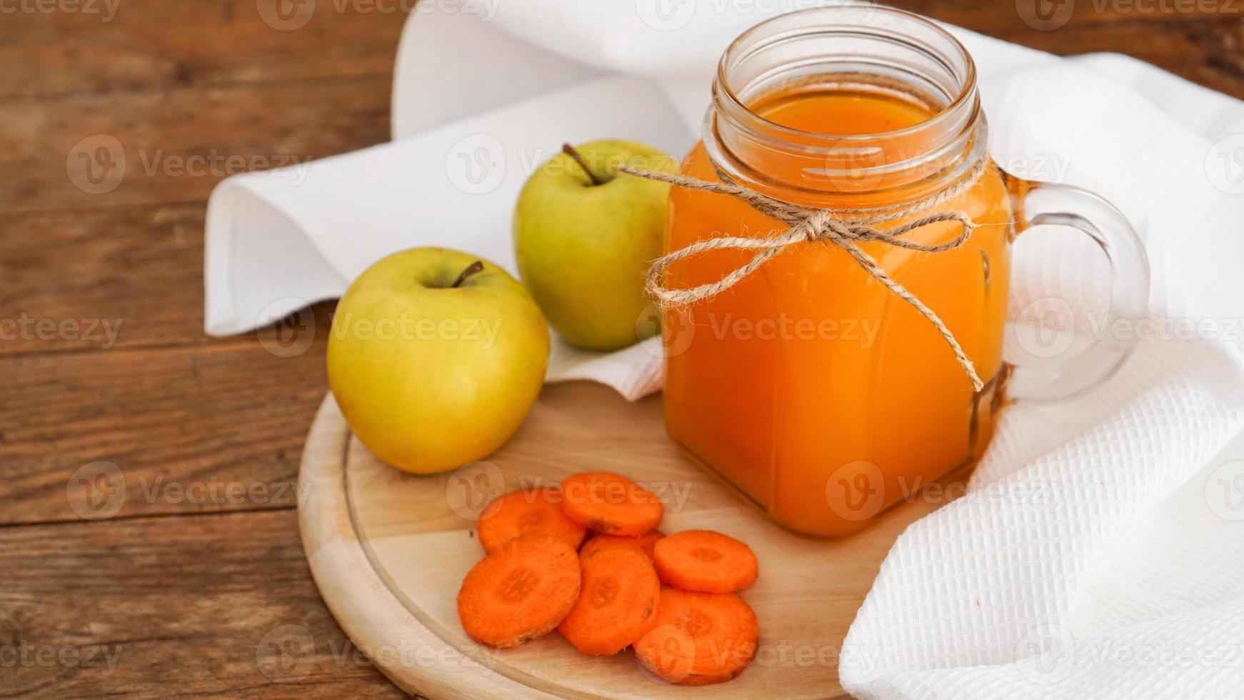 succo di mela e carota in vetro, verdure fresche e frutta su legno foto