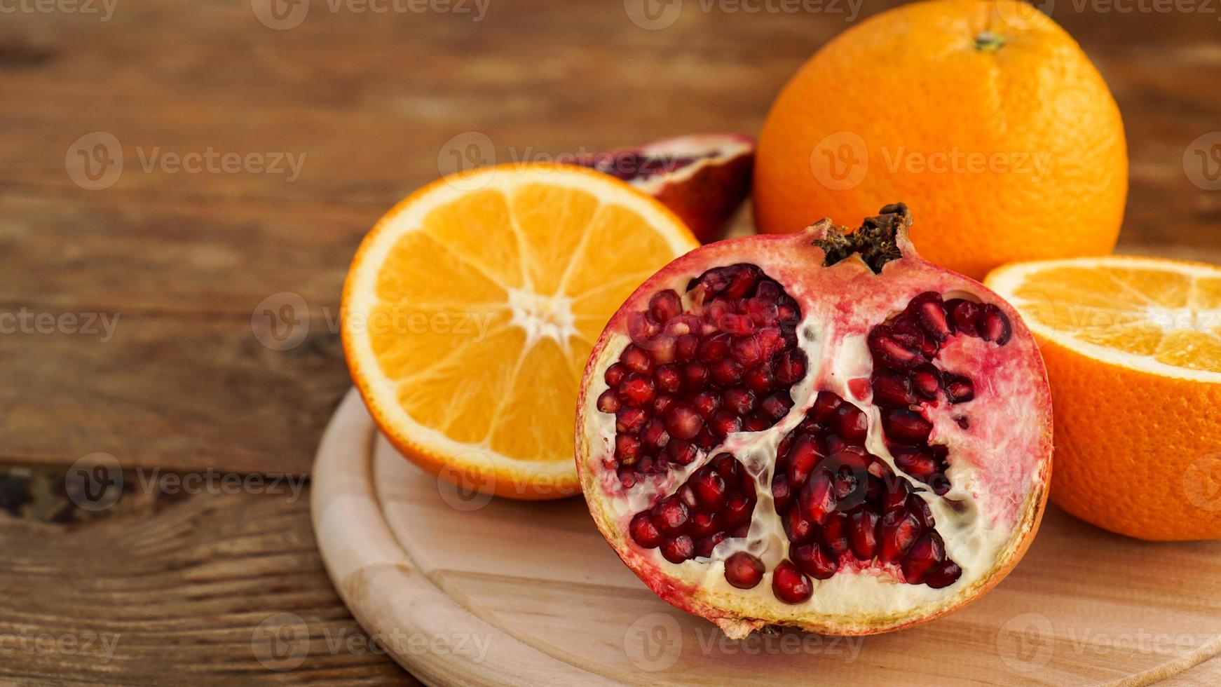 melograno e arance su un fondo di legno. frutta tagliata foto