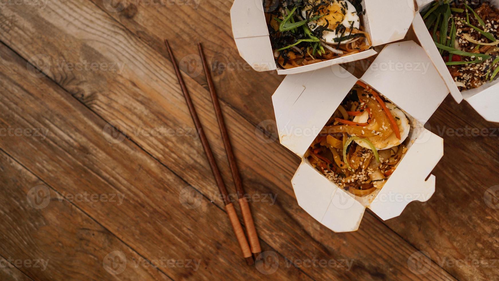 noodles con carne di maiale e verdure in scatola da asporto su tavola di legno foto