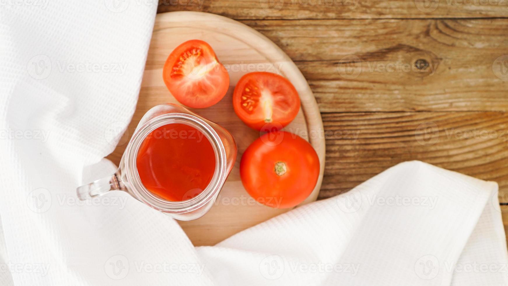 succo di pomodoro in barattolo di vetro e pomodori freschi su fondo di legno foto