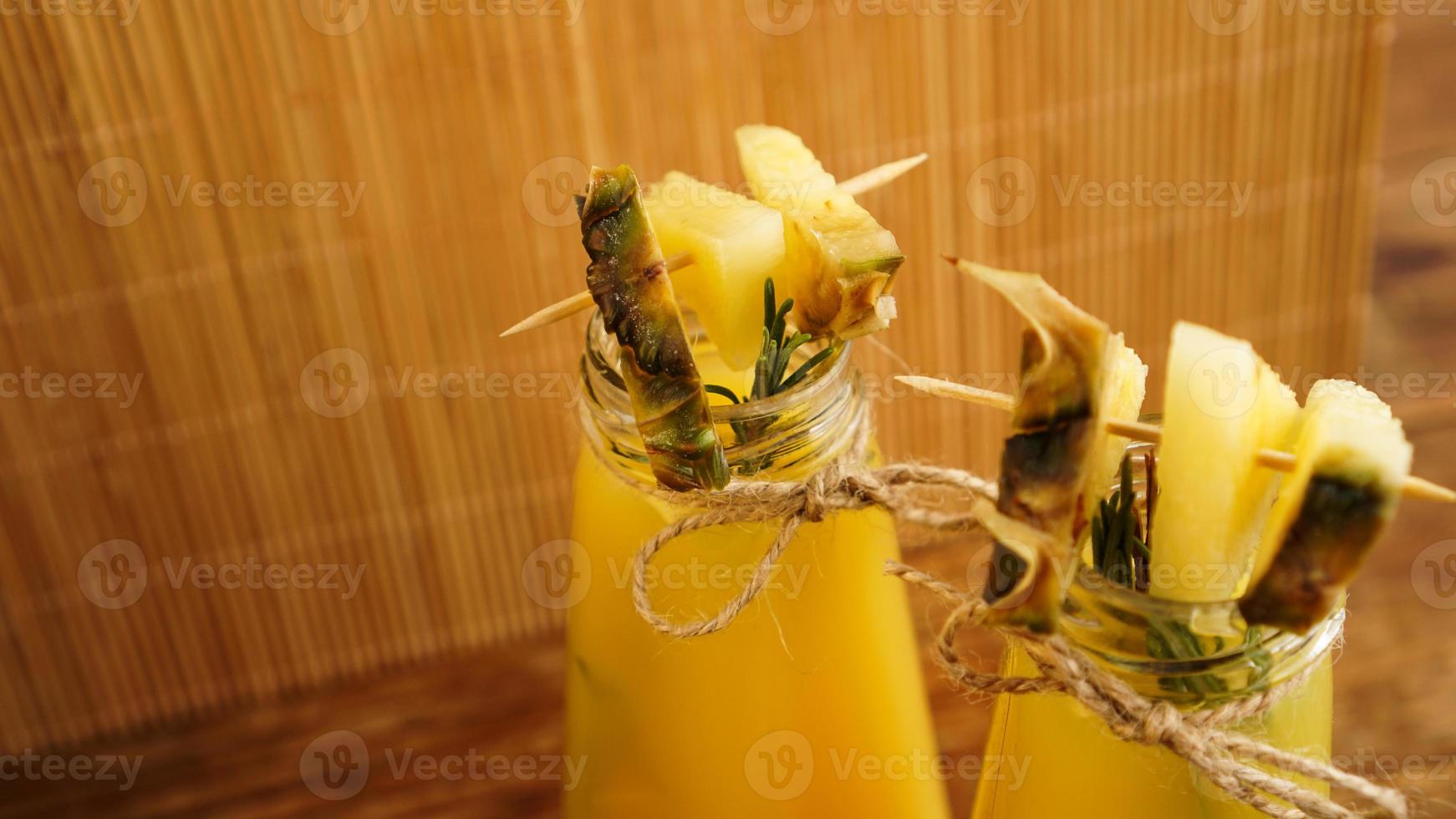 succo d'ananas in una bottiglietta. fette di ananas decorano la bevanda foto