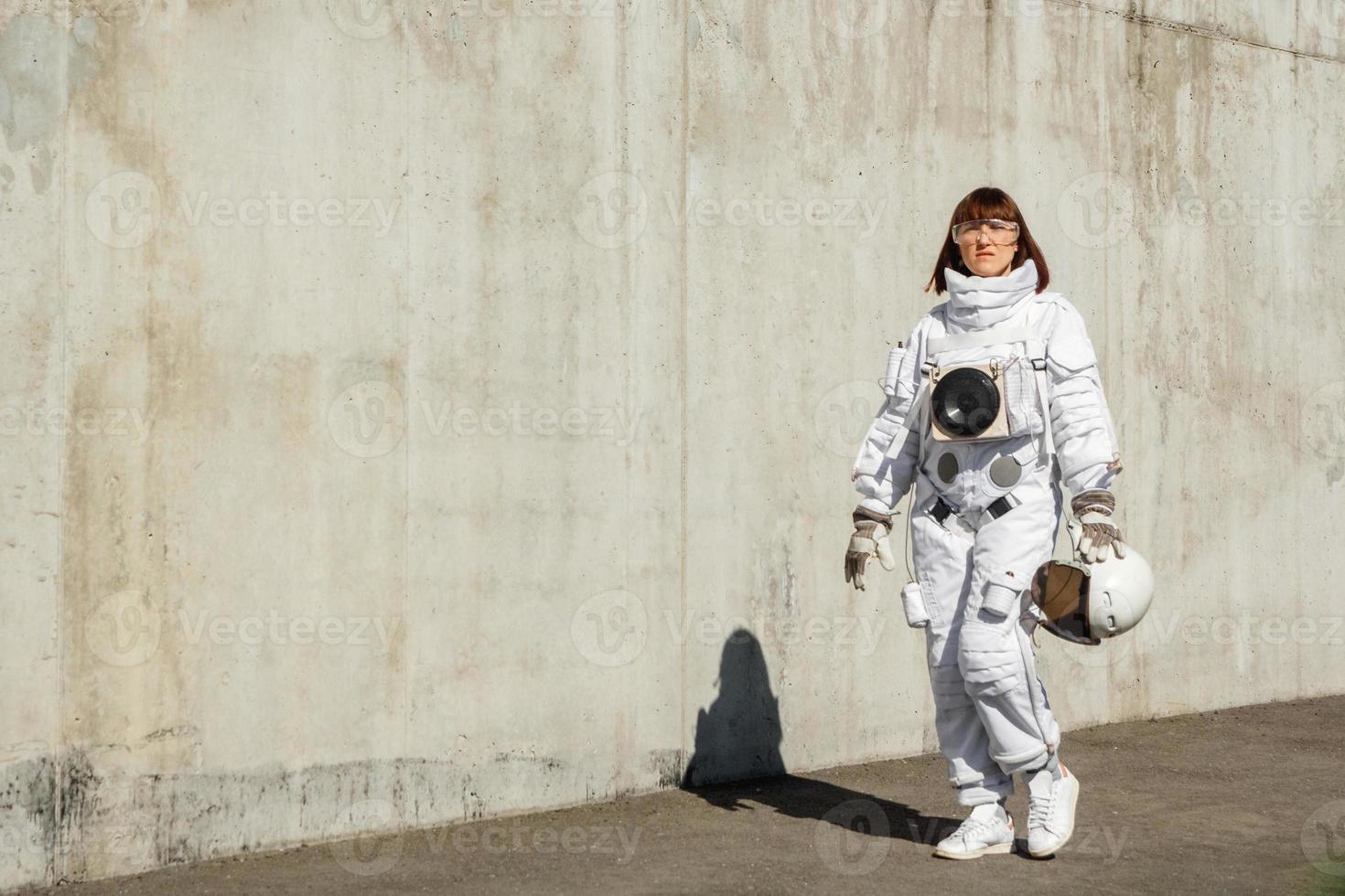 astronauta donna senza casco sullo sfondo di un muro grigio foto