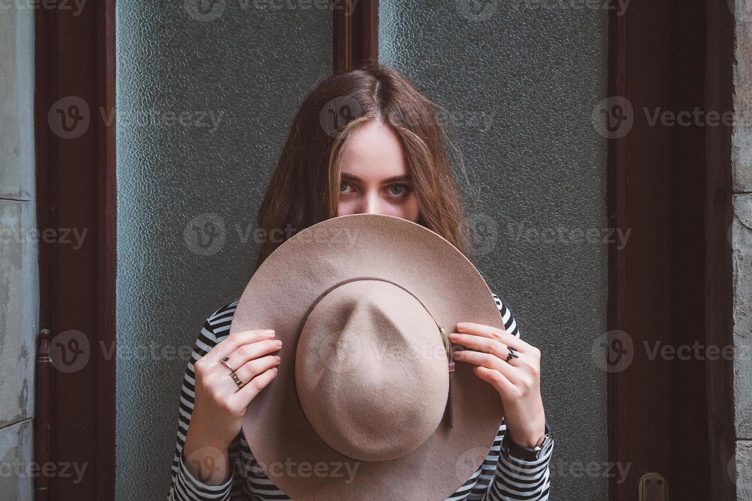 bella donna in una camicia a righe che tiene il suo cappello foto