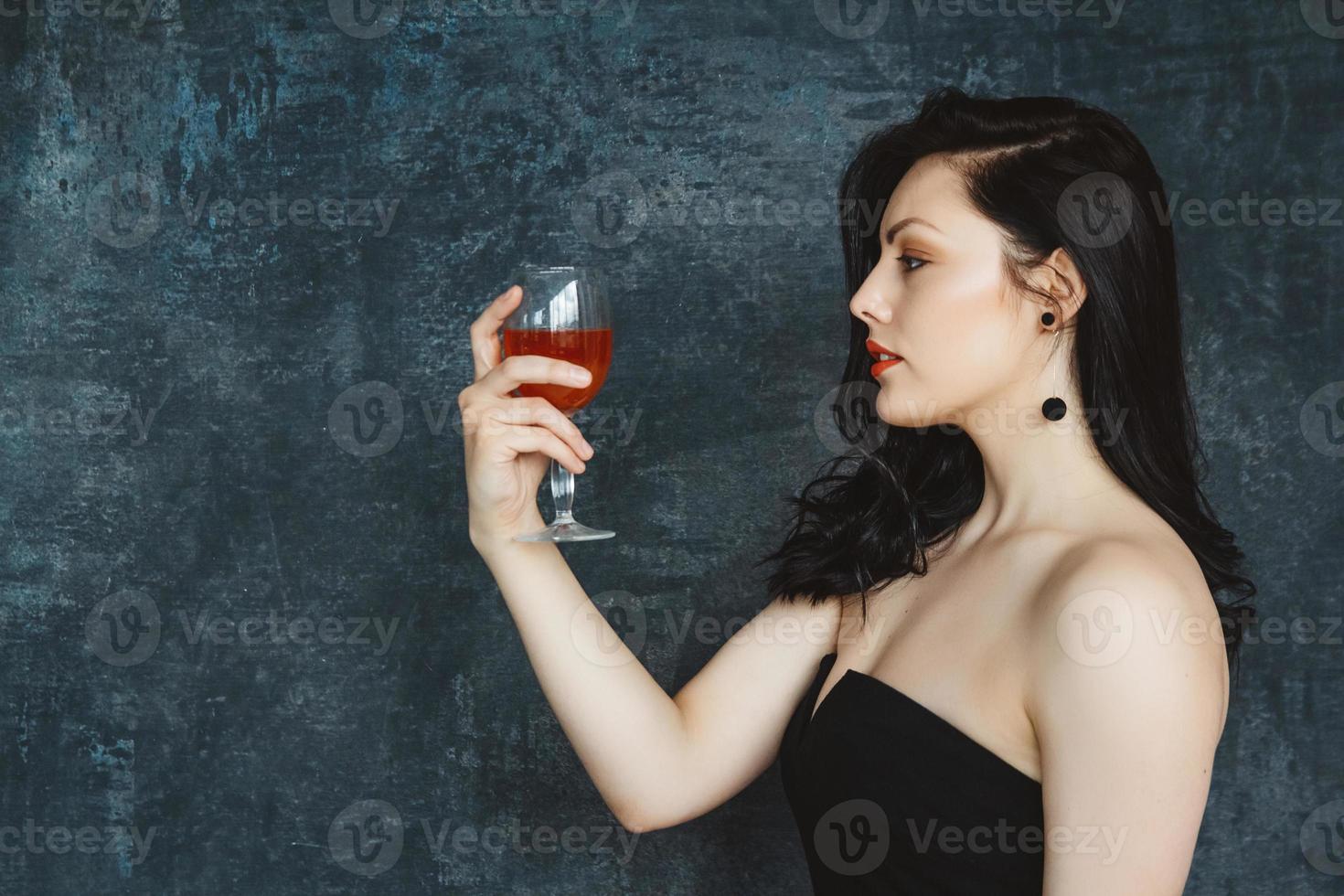 bella giovane donna con un bicchiere di vino su sfondo grigio foto