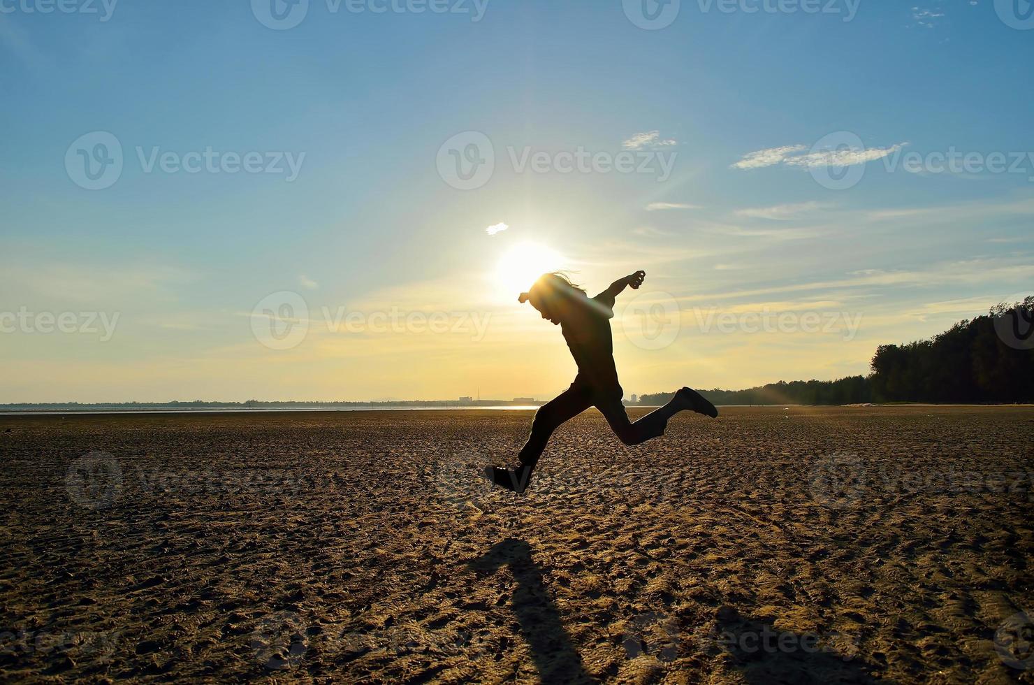 sagoma di bambino che corre sulla spiaggia al tramonto foto