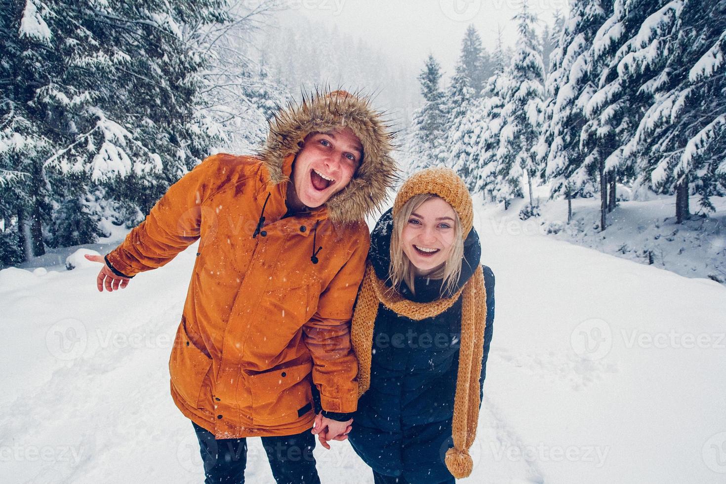 ragazzo e ragazza camminano e si divertono nella foresta in inverno foto