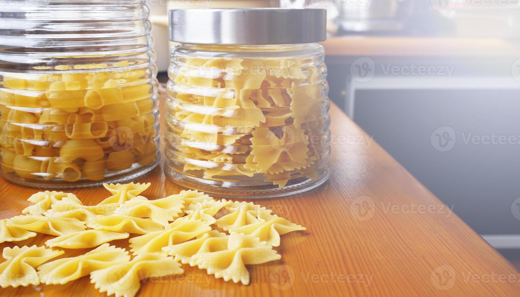 pasta a forma di fiocchi sparsi da un barattolo di vetro foto