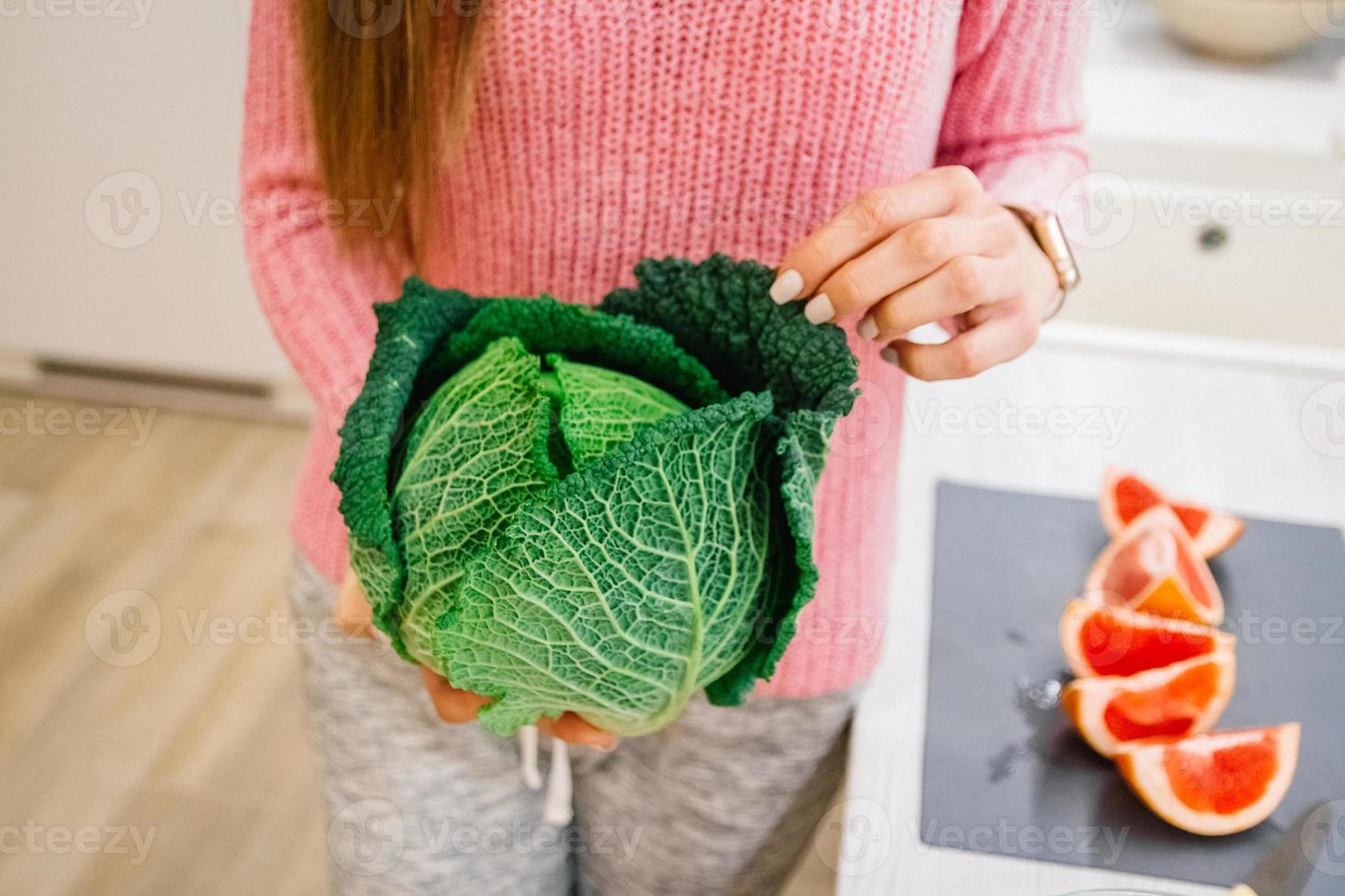 donna che tiene cavolo verde nella sua cucina foto