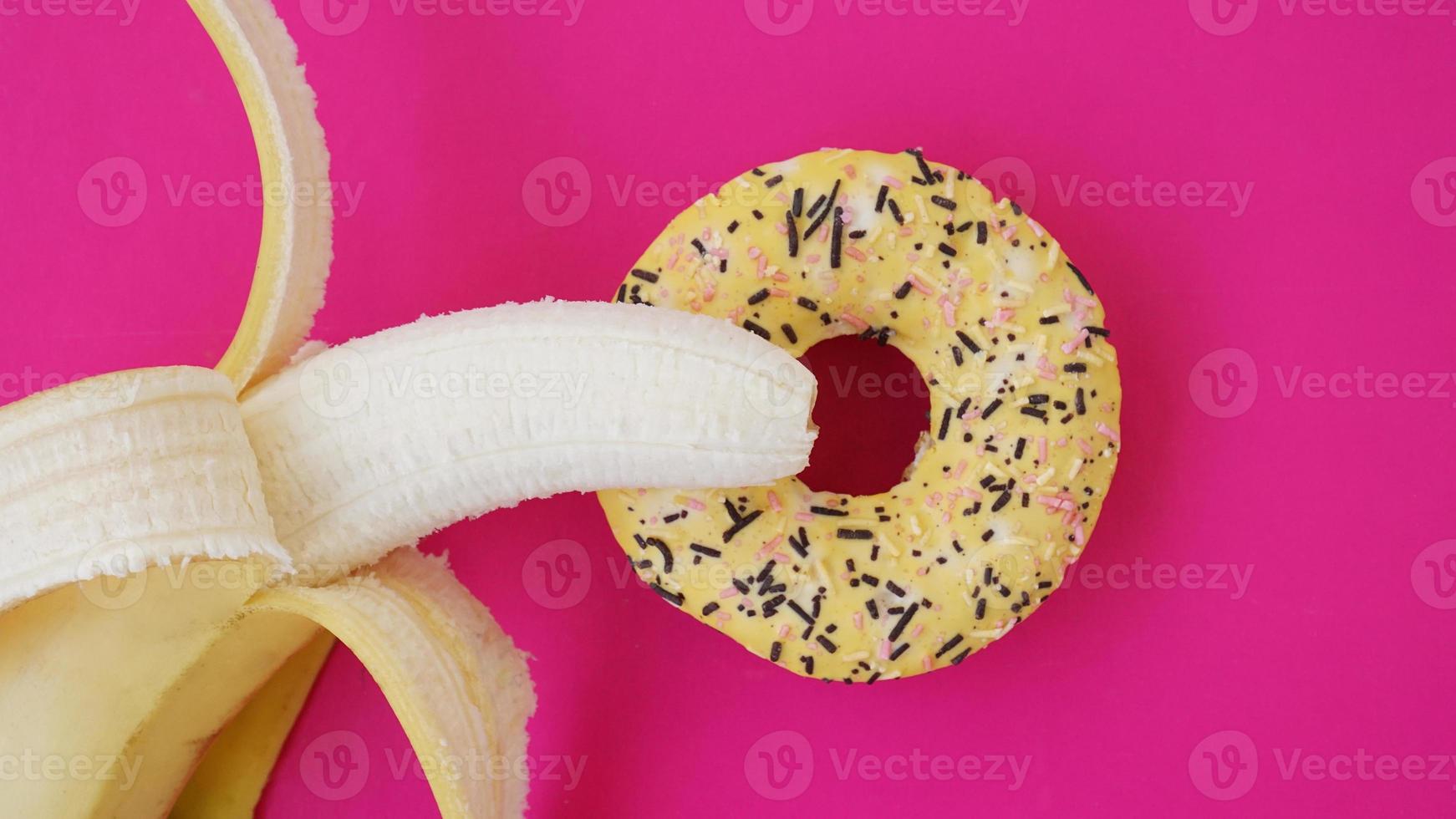 ciambella dolce e banana su sfondo di colore rosa. concetto erotico foto