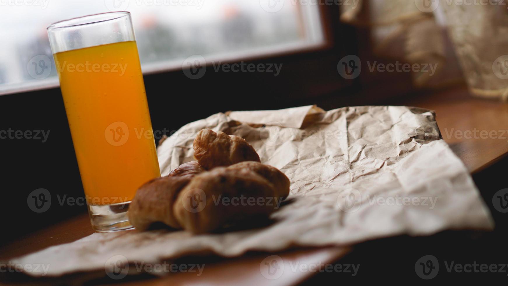 croissant appena sfornati con succo d'arancia su carta kraft foto