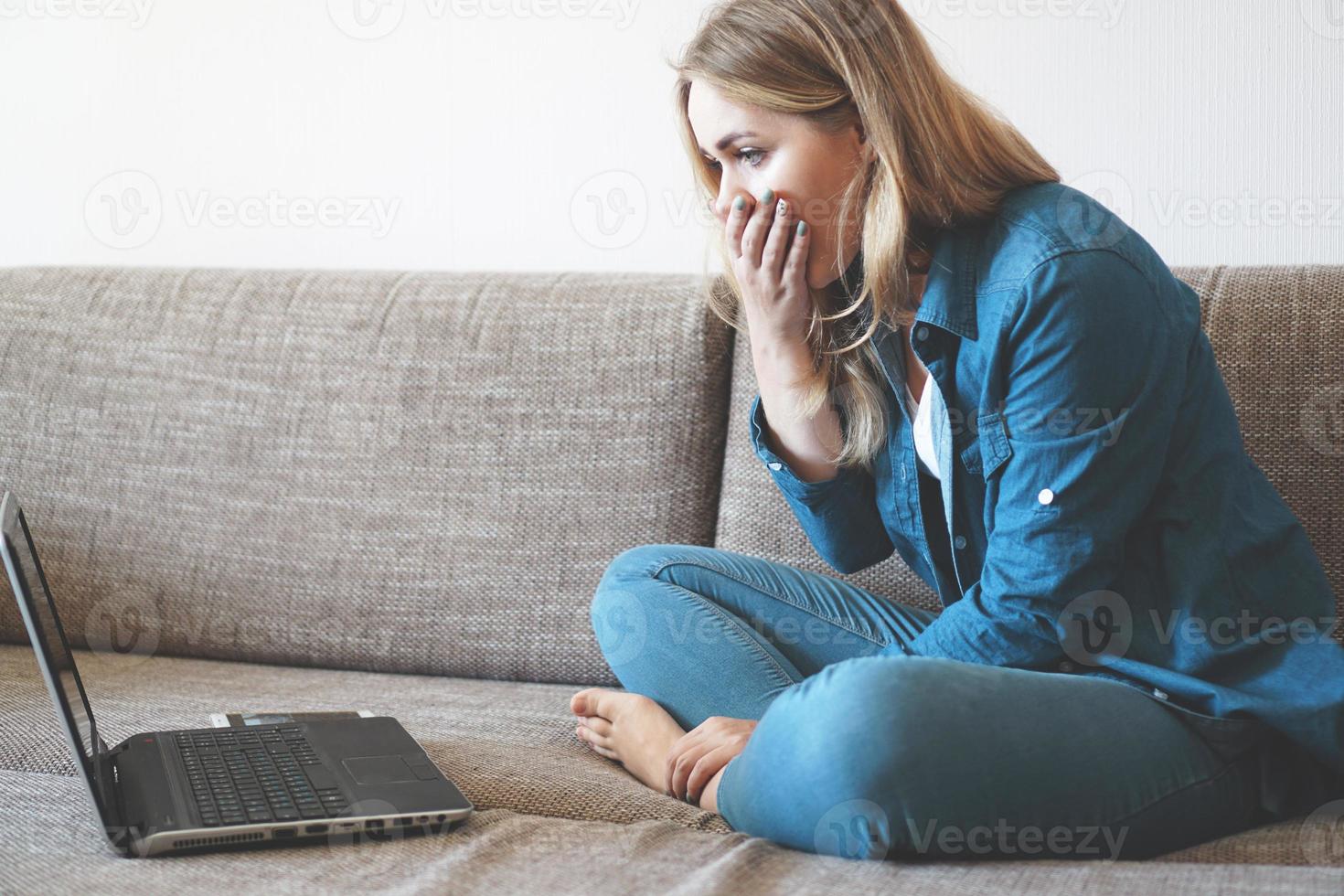 giovane donna scioccata che guarda lo schermo del laptop foto