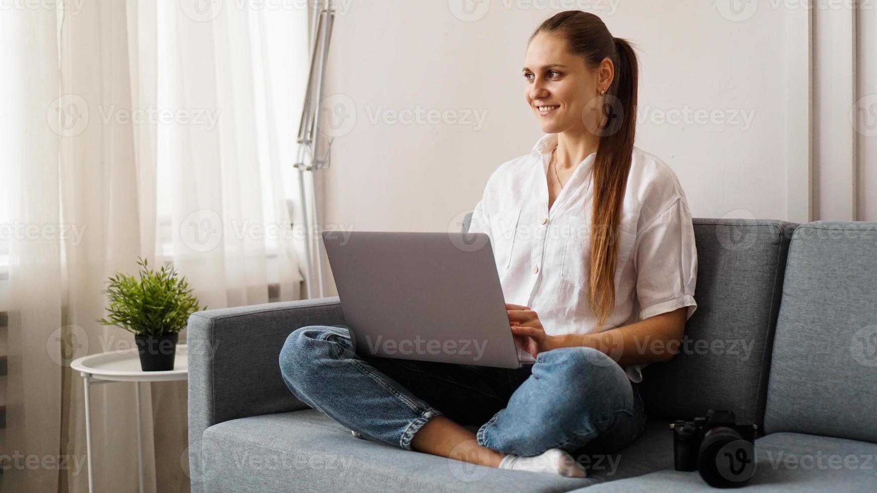 giovane donna felice che per mezzo del computer portatile a casa foto