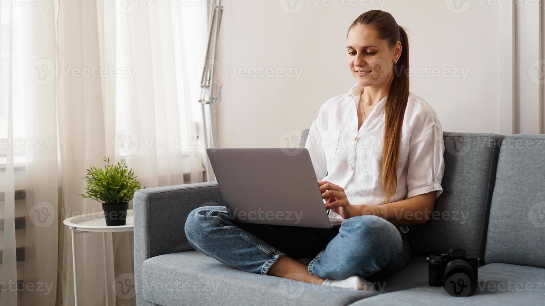 giovane donna felice che per mezzo del computer portatile a casa foto