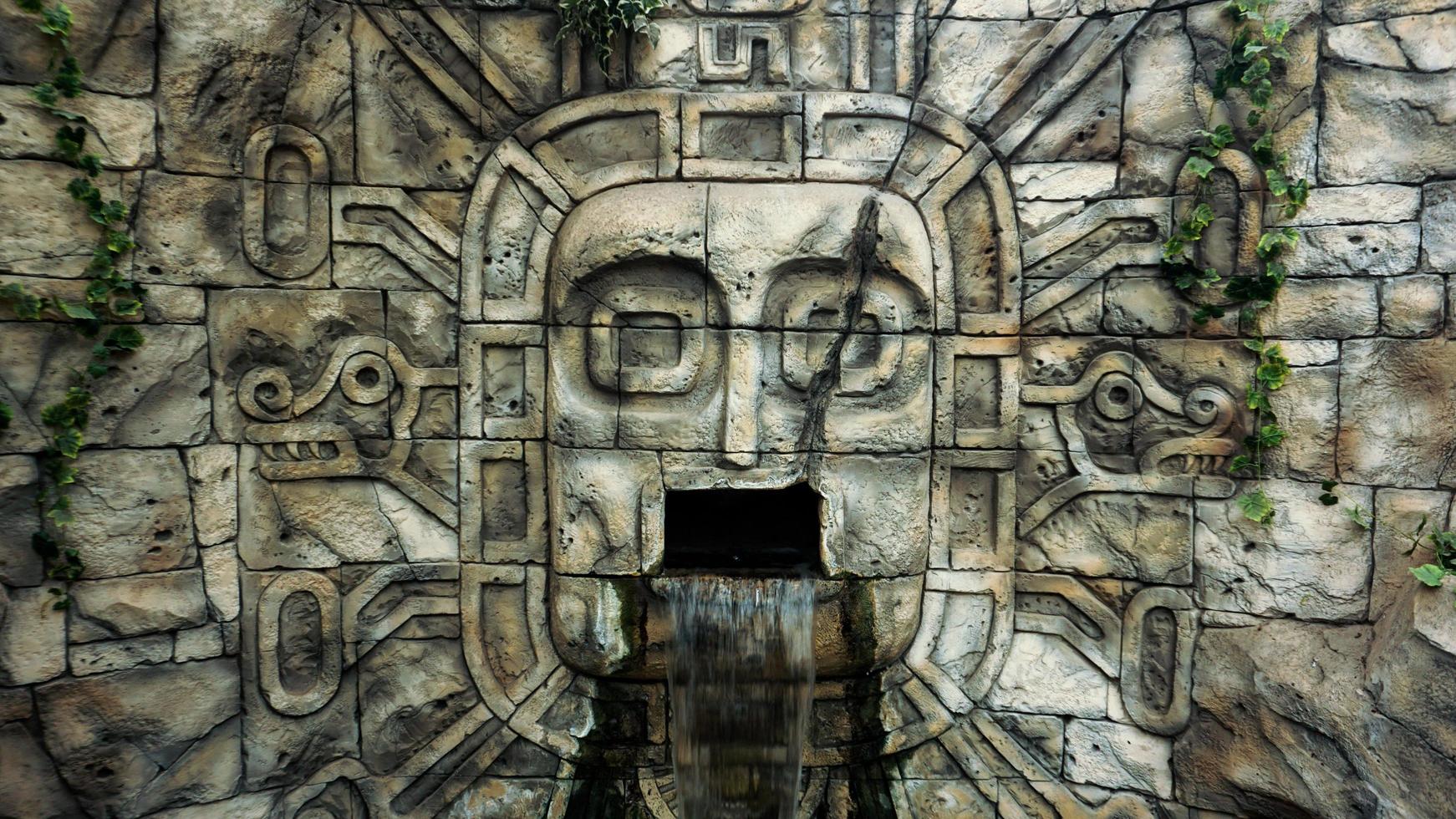 muro di pietra nella giungla. maschera per la testa e cascata dalla bocca foto