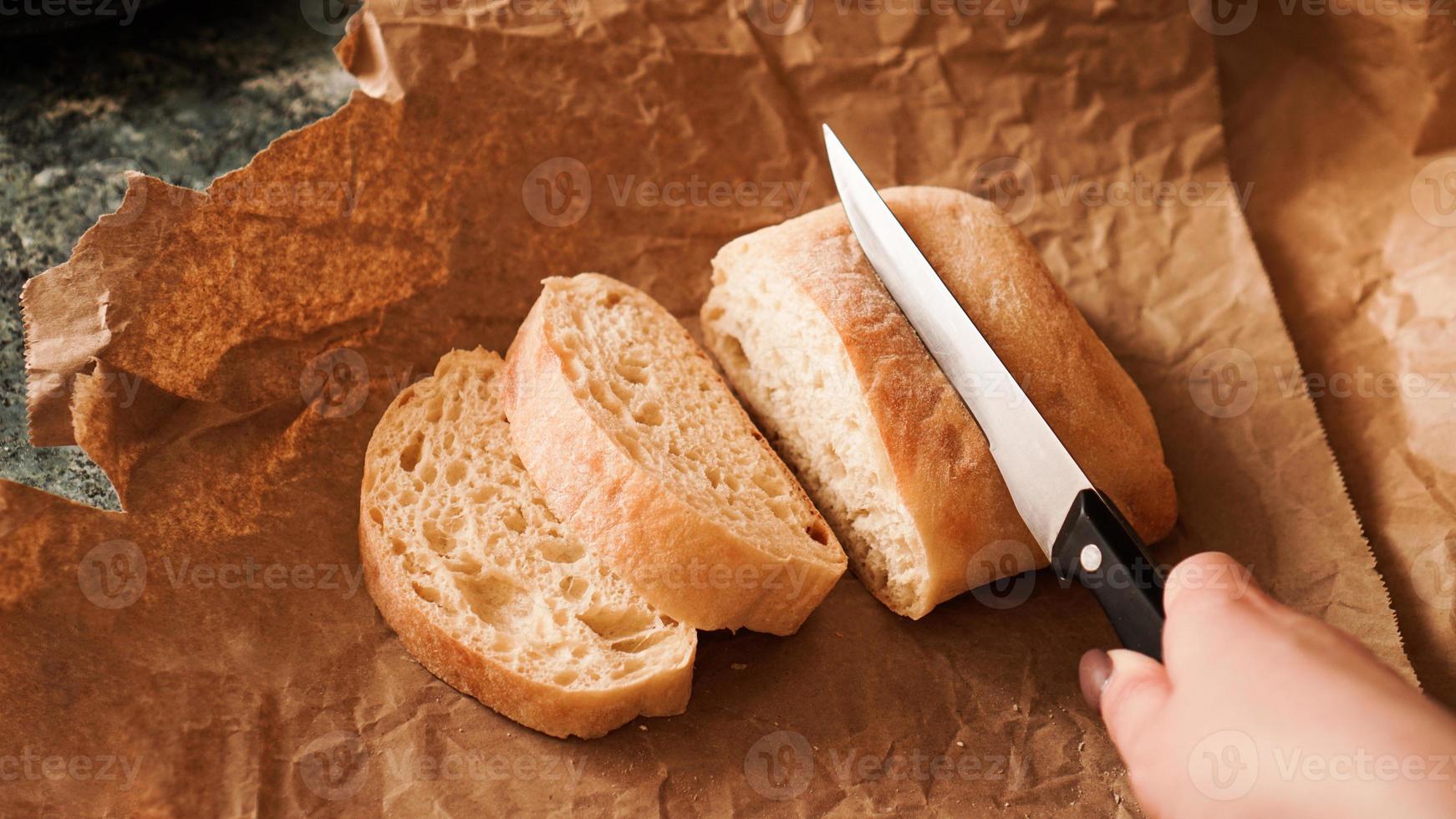 lo chef affetta la ciabatta con un coltello. foto