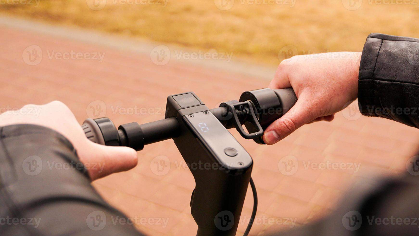 primo piano della mano maschile che preme il pulsante di velocità su scooter elettrico foto