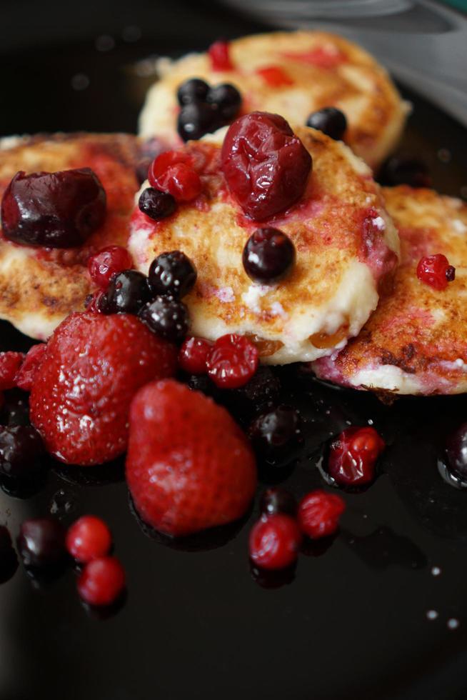 frittelle di formaggio con frutti di bosco su un piatto nero. foto