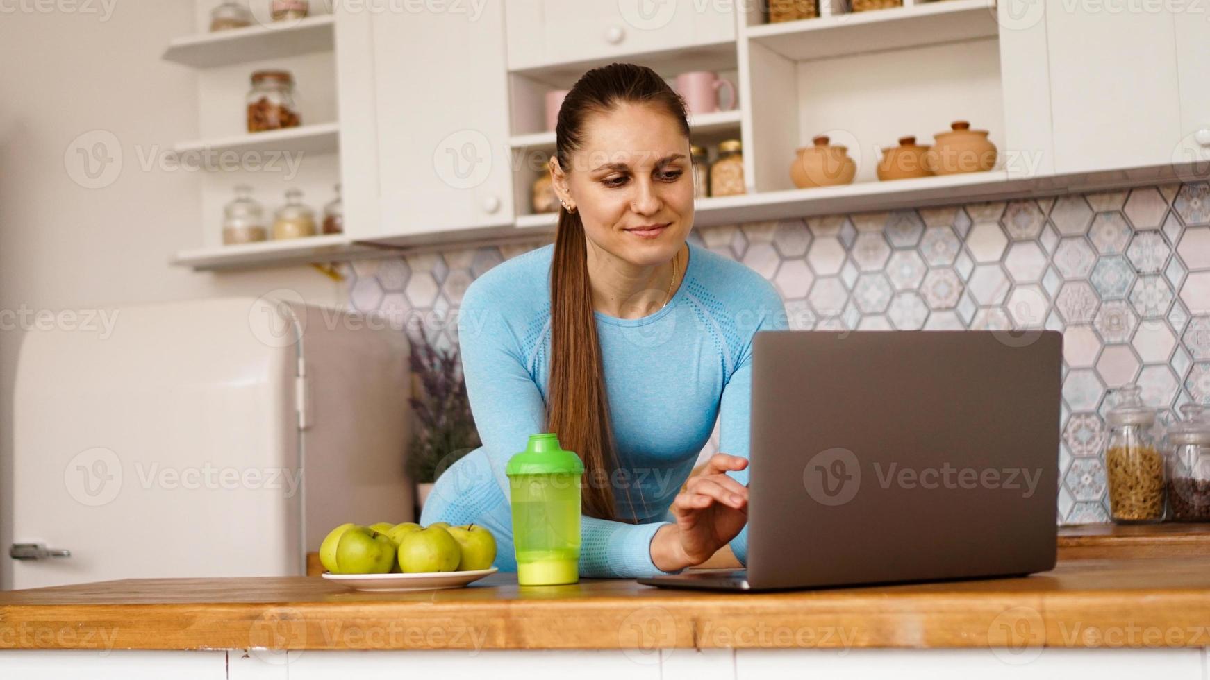 donna sorridente che usa il computer nella cucina moderna foto