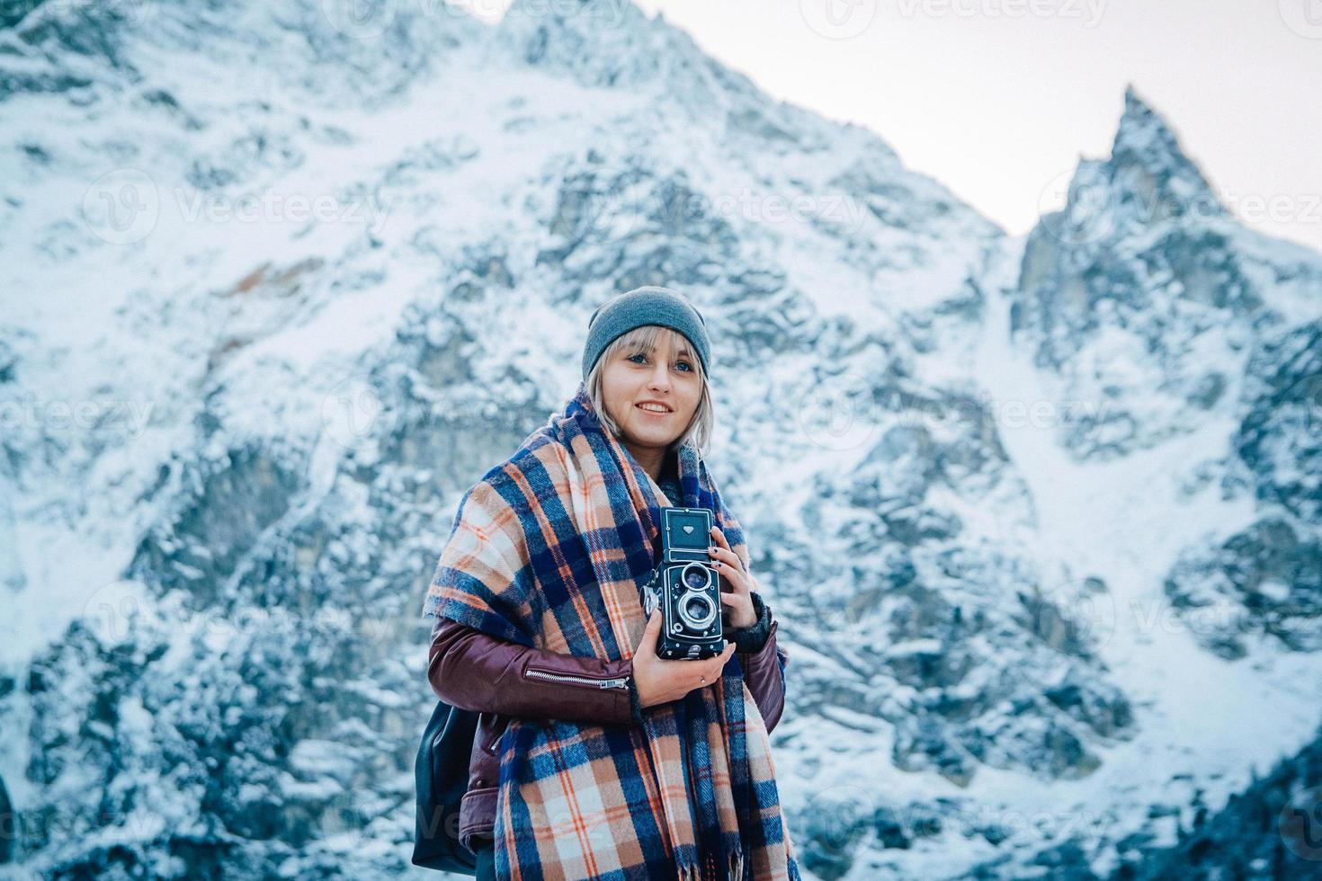 ragazza con la vecchia macchina fotografica d'epoca su uno sfondo di montagne di neve foto