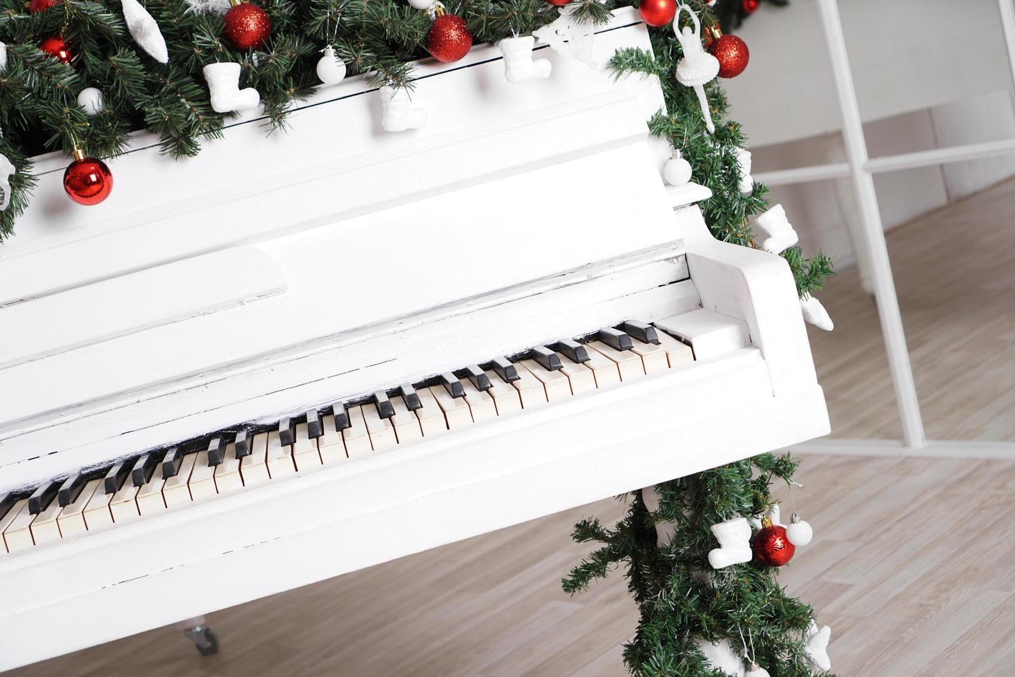 tasti su pianoforte verticale bianco con decorazioni natalizie foto
