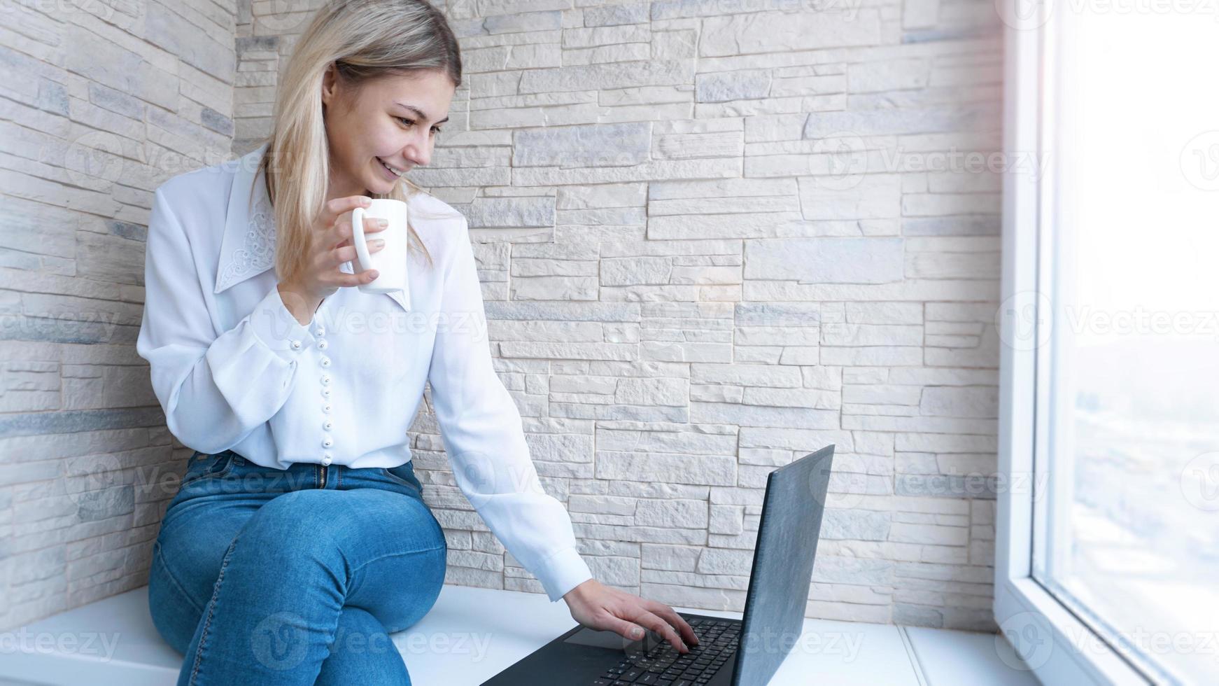 vista laterale. giovane donna d'affari con una tazza di caffè e notebook. foto