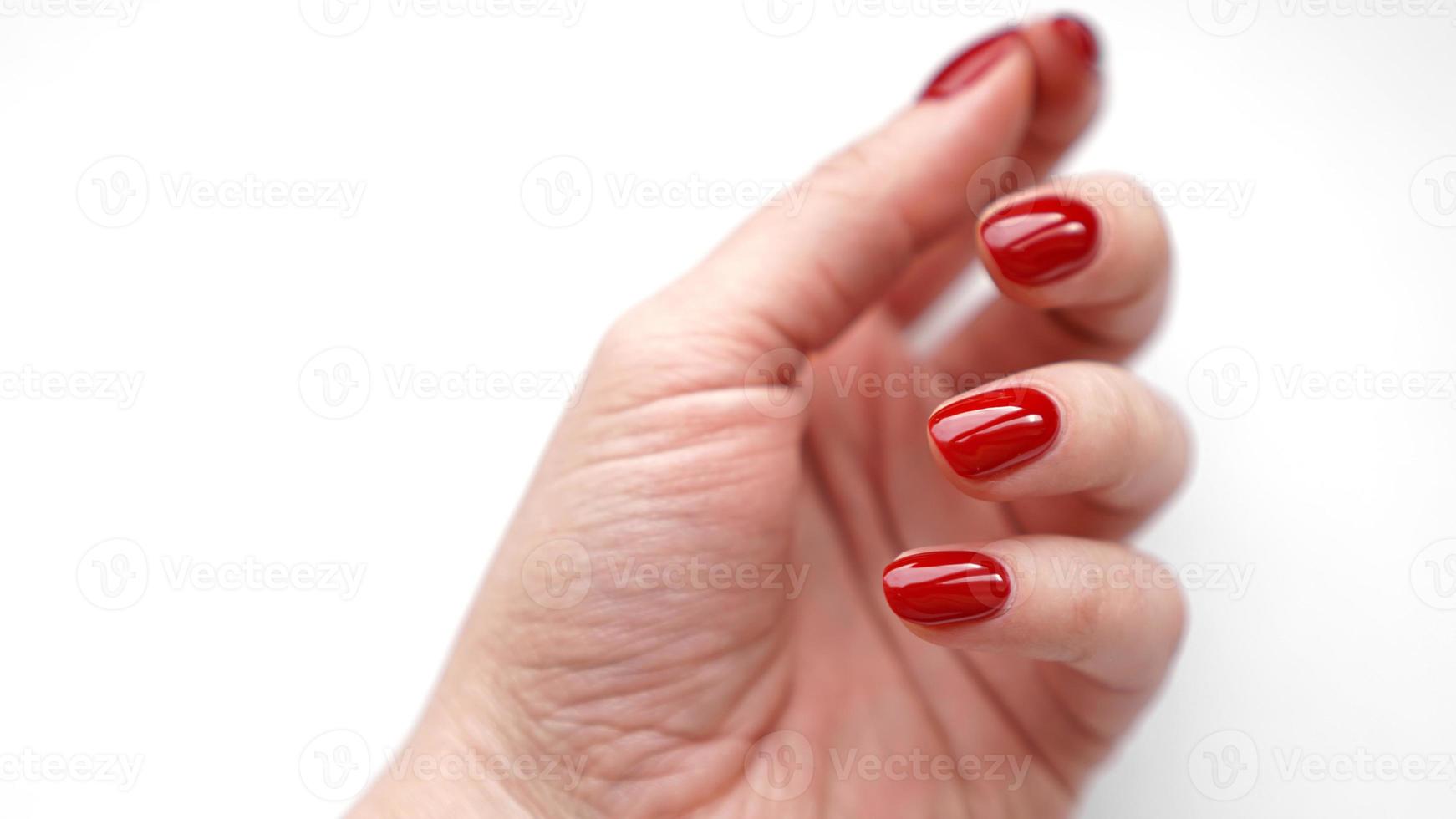 bella mano femminile con manicure rossa e unghie isolate su bianco foto