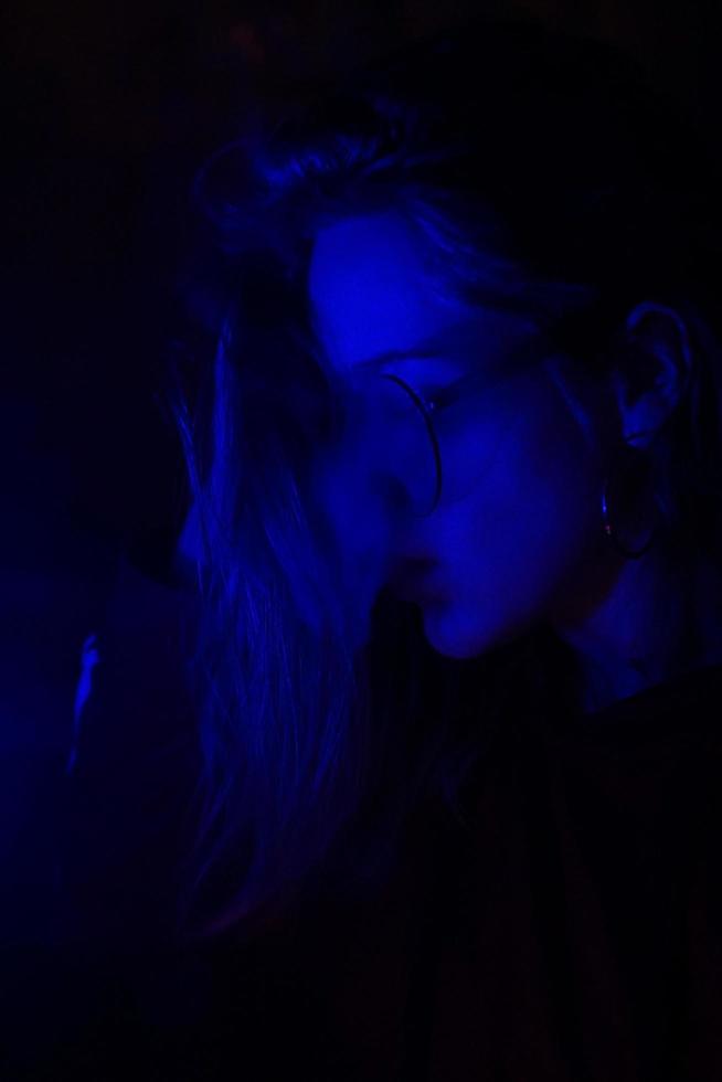 ritratto ravvicinato di una ragazza che svapa con una luce blu al neon foto