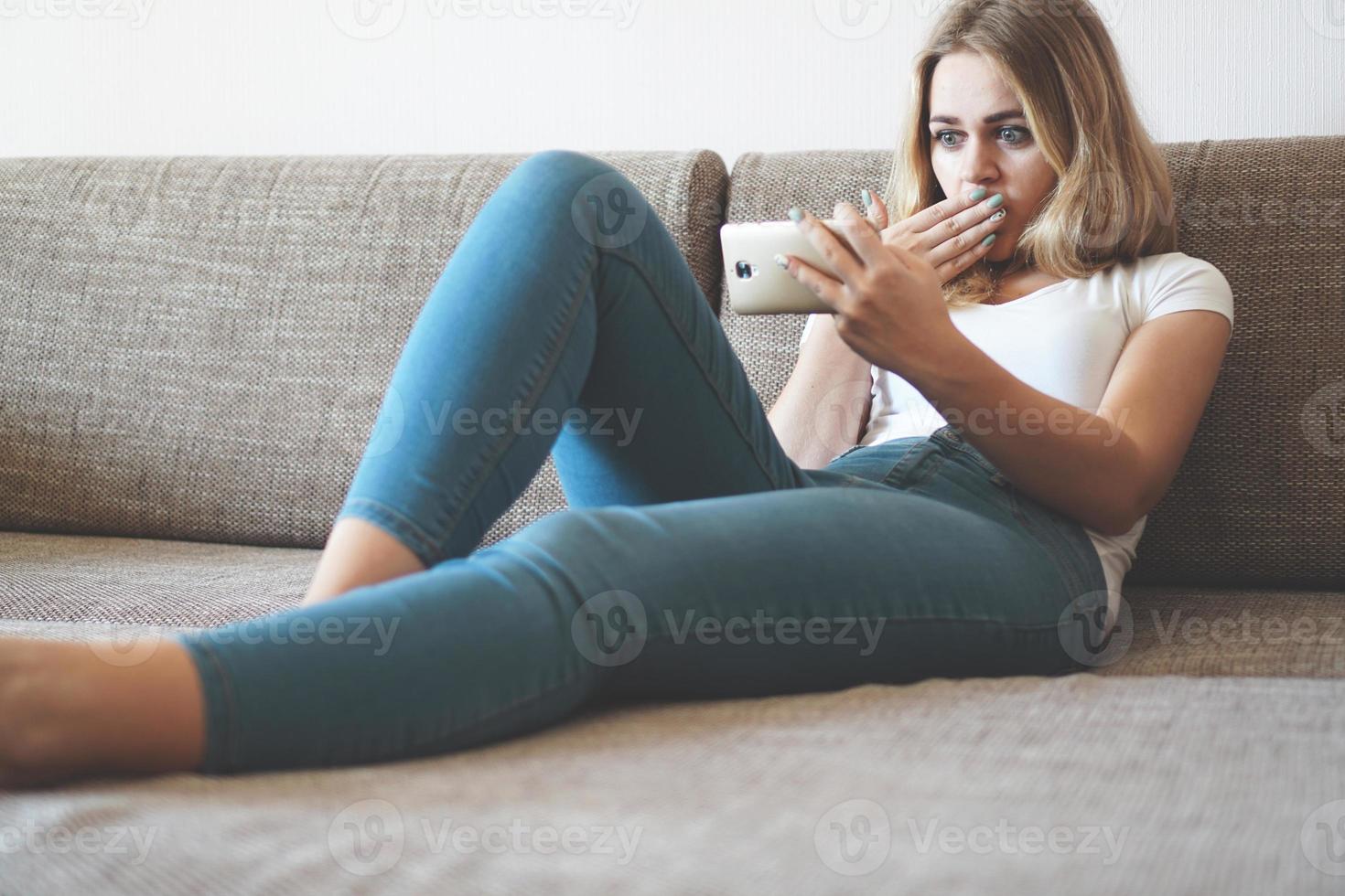 giovane donna scioccata che guarda lo smartphone foto