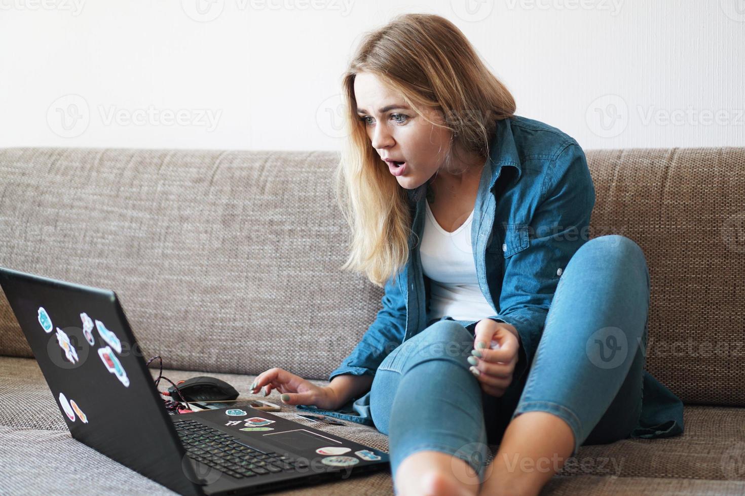 giovane donna scioccata che guarda lo schermo del laptop foto