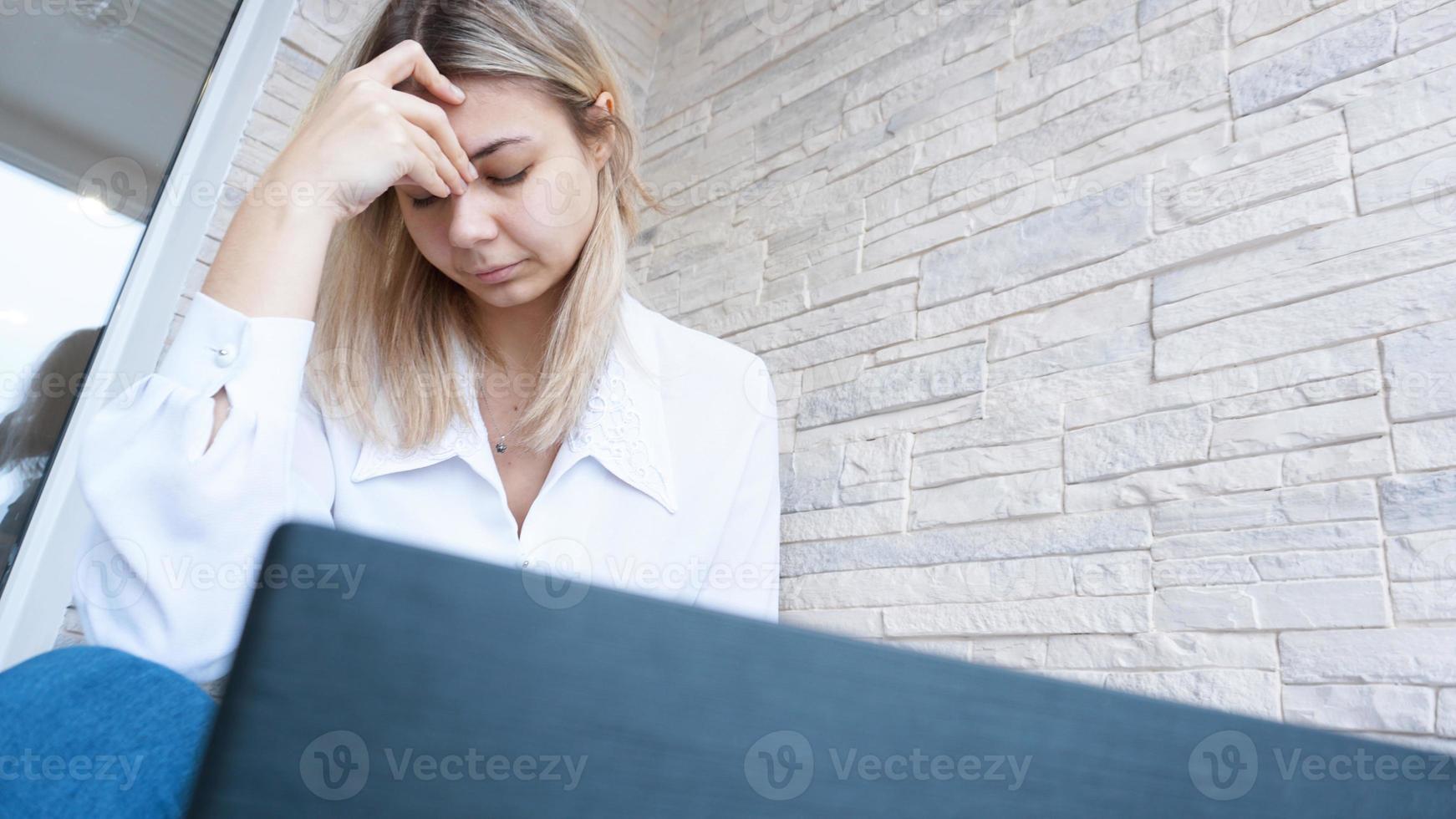 la donna guarda il suo laptop con un'espressione preoccupata addolorata foto