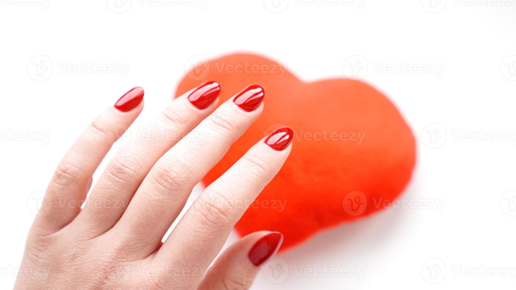 mano femminile con cuore rosso isolato su bianco foto