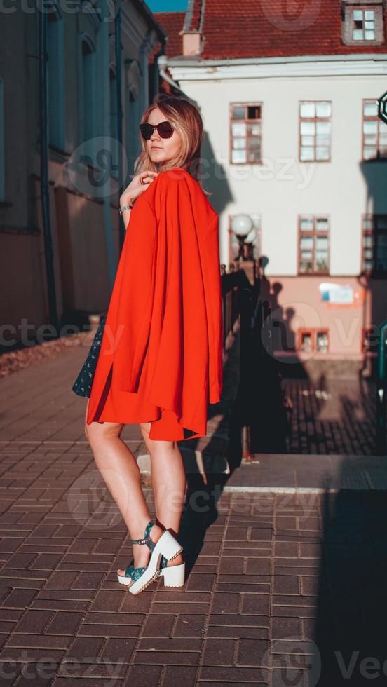 bella giovane donna in giacca rossa sullo sfondo urbano della strada della città foto