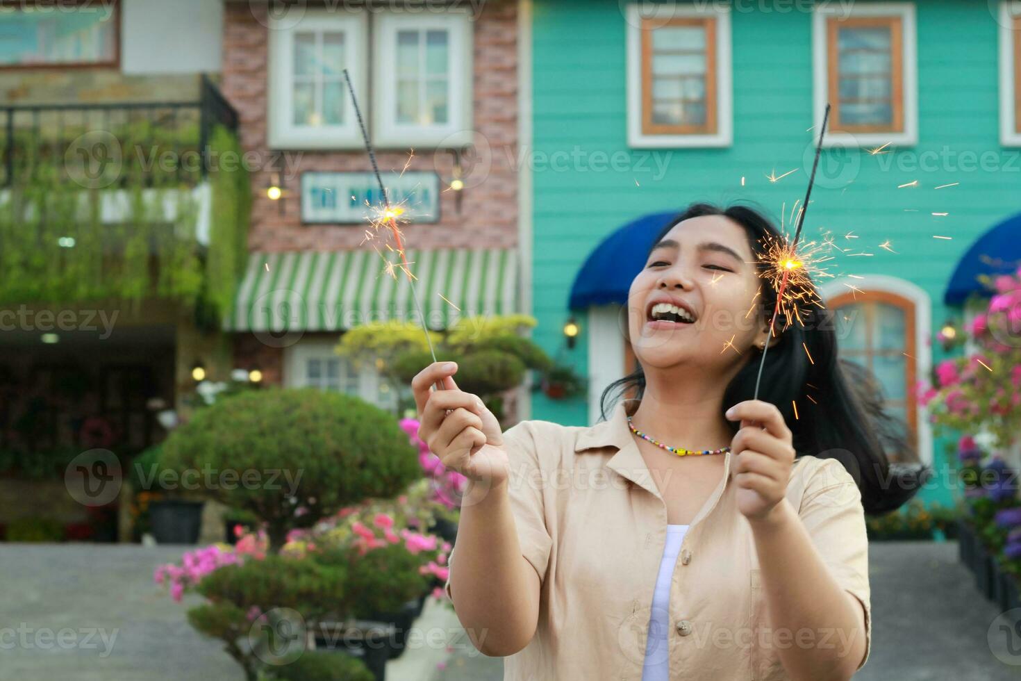 ritratto di bellissimo contento giovane asiatico donna Tenere sparklers fuochi d'artificio per celebrare nuovo anno vigilia con giardino festa in piedi nel all'aperto Vintage ▾ Casa cortile foto