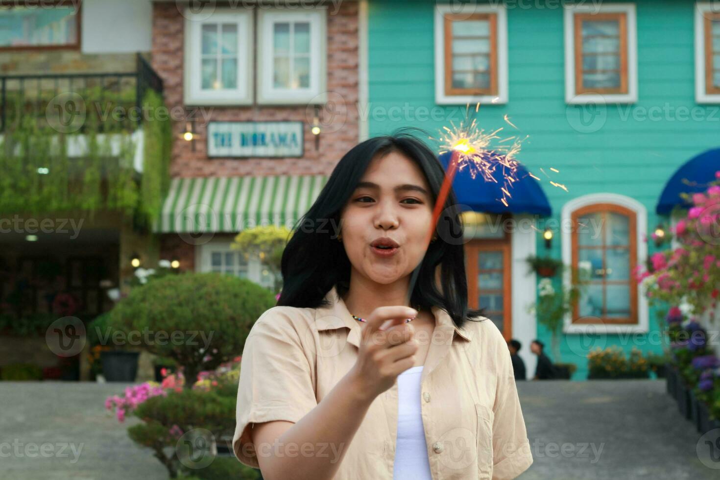 ritratto di bellissimo contento giovane asiatico donna Tenere sparklers fuochi d'artificio per celebrare nuovo anno vigilia con giardino festa in piedi nel all'aperto Vintage ▾ Casa cortile foto