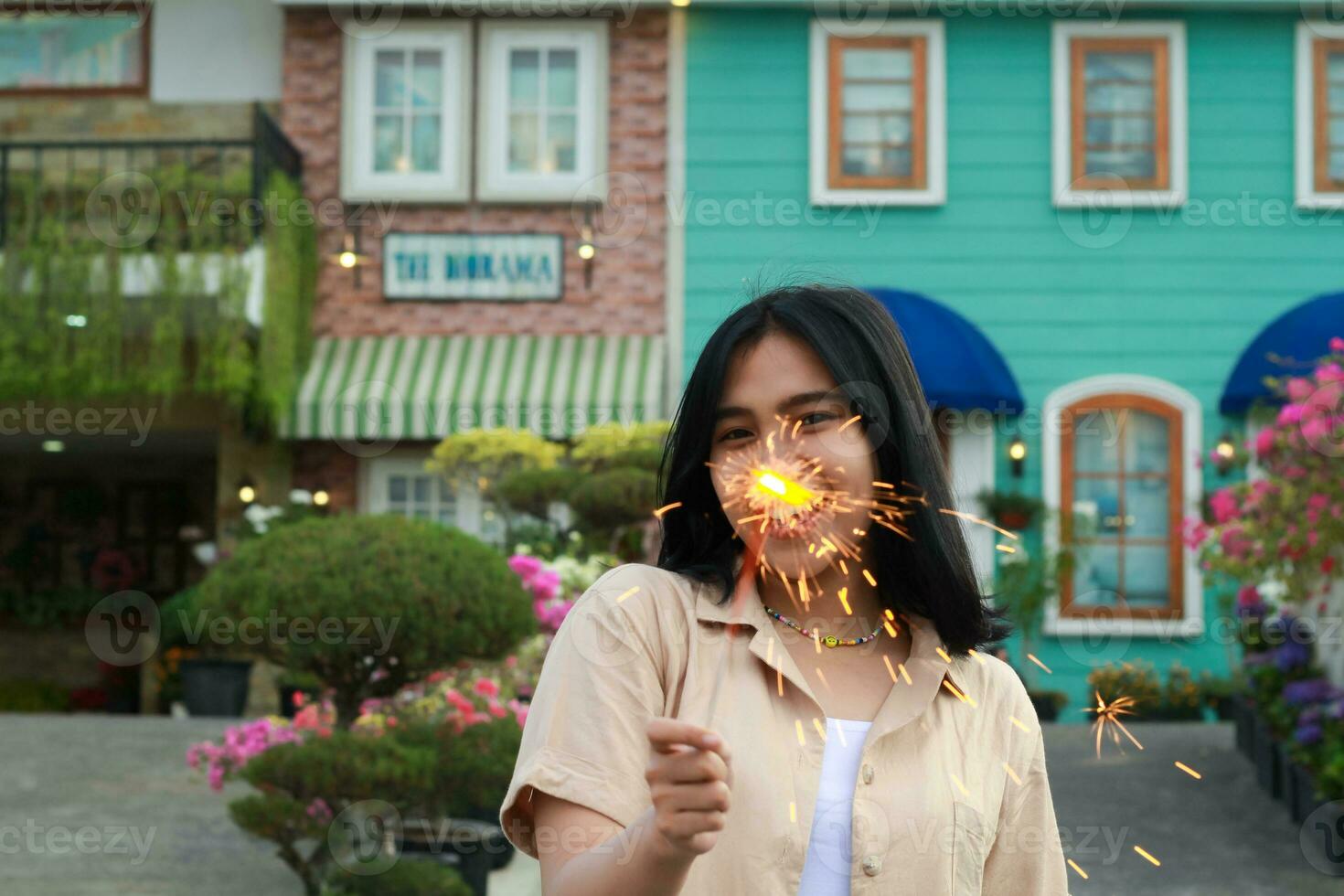 ritratto di bellissimo contento giovane asiatico donna Tenere sparklers fuochi d'artificio per celebrare nuovo anno vigilia con giardino festa in piedi nel all'aperto Vintage ▾ Casa cortile foto