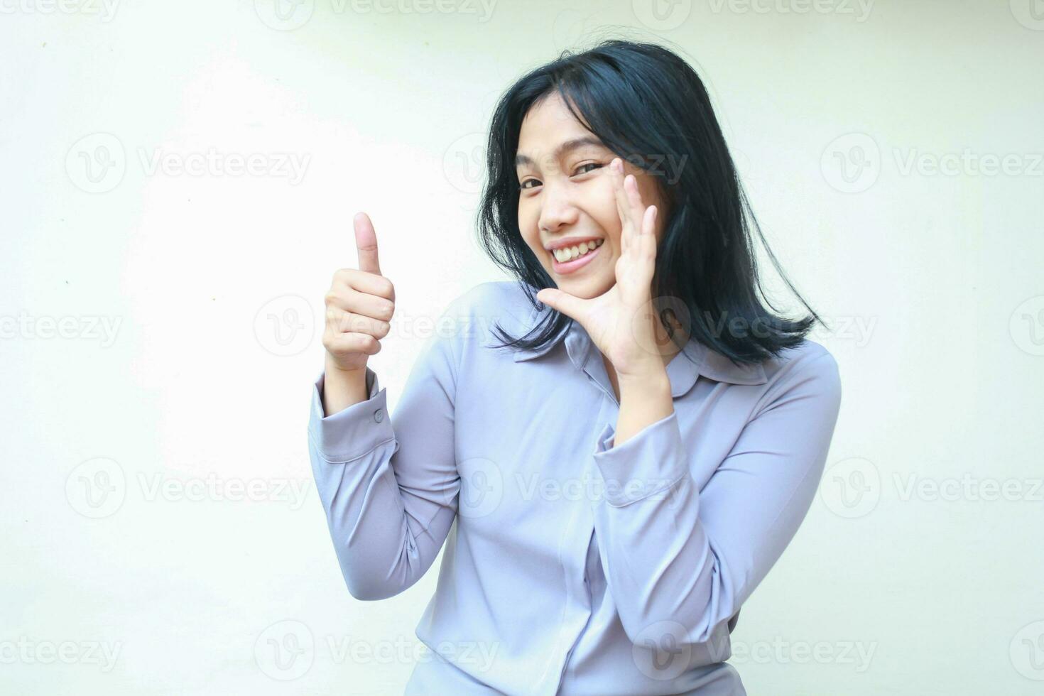 soddisfatto bella asiatico giovane attività commerciale donna sorridente per telecamera con contento viso espressione dando pollici su approvazione cartello indossare formale viola camicia in piedi isolato al di sopra di bianca sfondo foto
