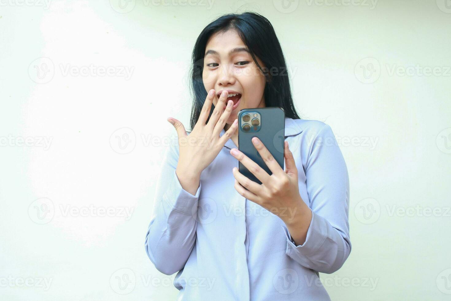 scioccato asiatico giovane attività commerciale donna stordito e copertura sua bocca mentre guardare mobile Telefono indossare formale camicia in piedi al di sopra di isolato bianca sfondo foto