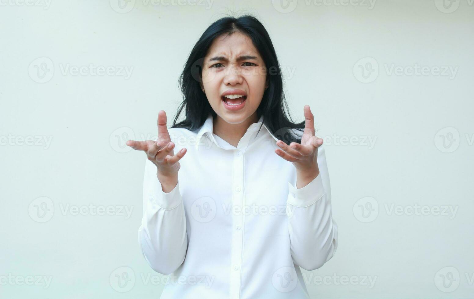 che cosa fare voi volere. arrabbiato asiatico donna guardare a telecamera con accigliato viso espressione e alzando le spalle le spalle mantenere palme lateralmente interrogativo gesto indossare bianca formale ufficio Abiti isolato foto