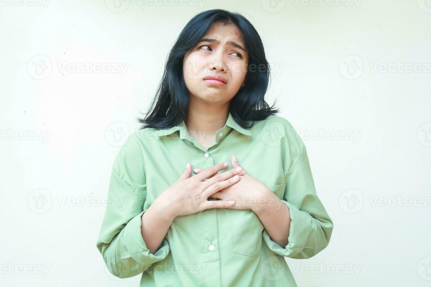 triste asiatico donna con buio capelli indossare verde camicia guardare a parte per vuoto spazio con preoccupazione viso espressione avere troppi pensieri e ansia, in piedi al di sopra di isolato bianca sfondo foto