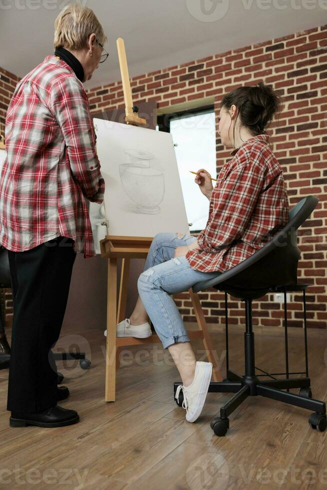 adulto figlia e anziano madre fare arte insieme mentre frequentando disegno officina, apprendimento per disegno, sviluppando Comune interessi e hobby. insegnante e alunno guardare a tela con opera d'arte foto