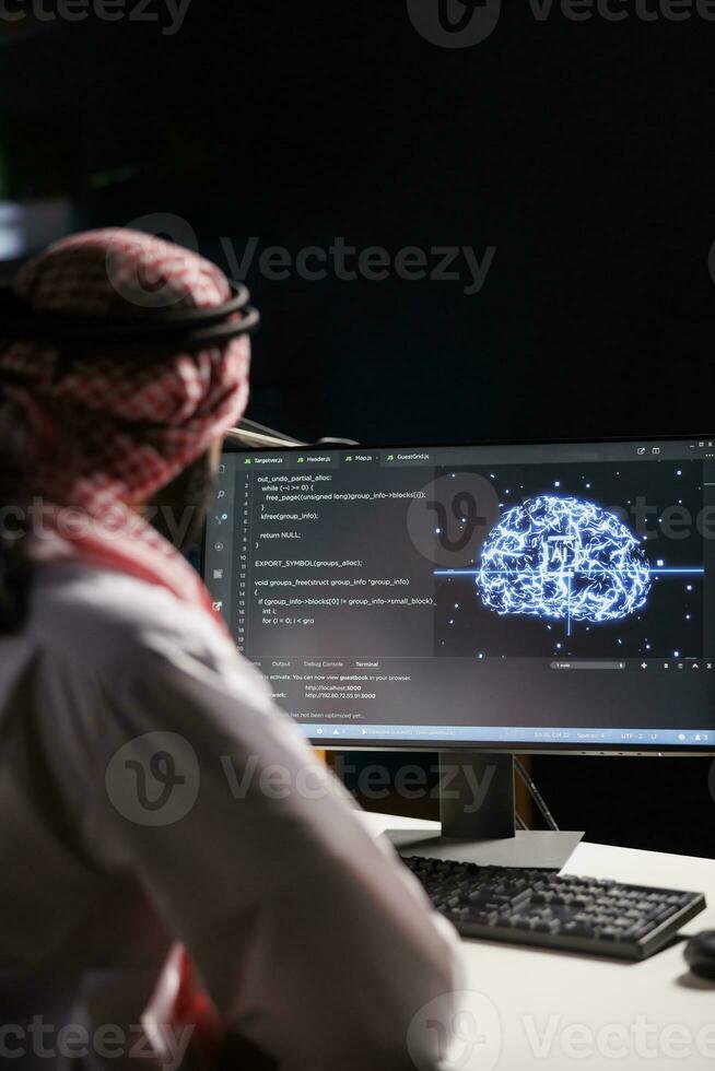 musulmano tipo Lavorando con codice e ai interfaccia su un' del desktop computer. lui è un' professionale sviluppatore gestione dati su un' in rete server nel un' basato su cloud dati centro. foto