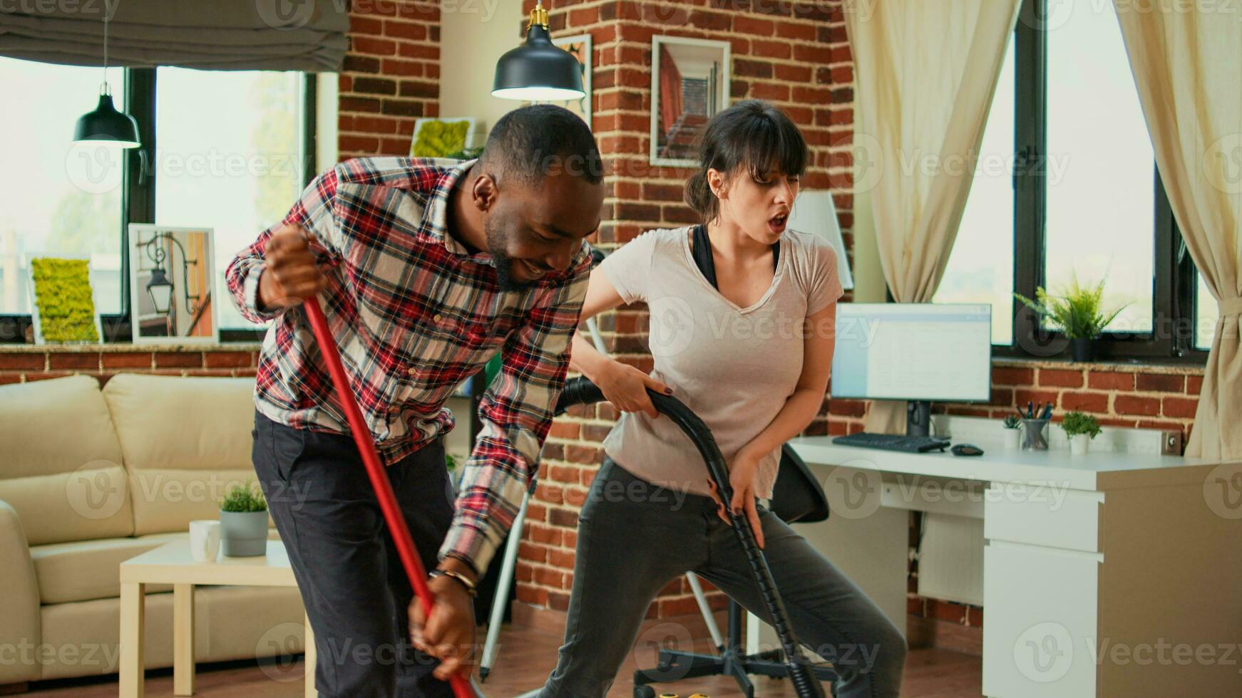 diverso coppia mostrando danza si sposta e avendo divertimento pulizia appartamento, utilizzando Mocio per spazzare polvere e vuoto a casa. vita partner danza e cantando, utilizzando lavaggio soluzione, primavera pulizia. foto